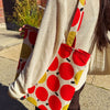 Person holding a tote bag with red and yellow polka dot pattern.