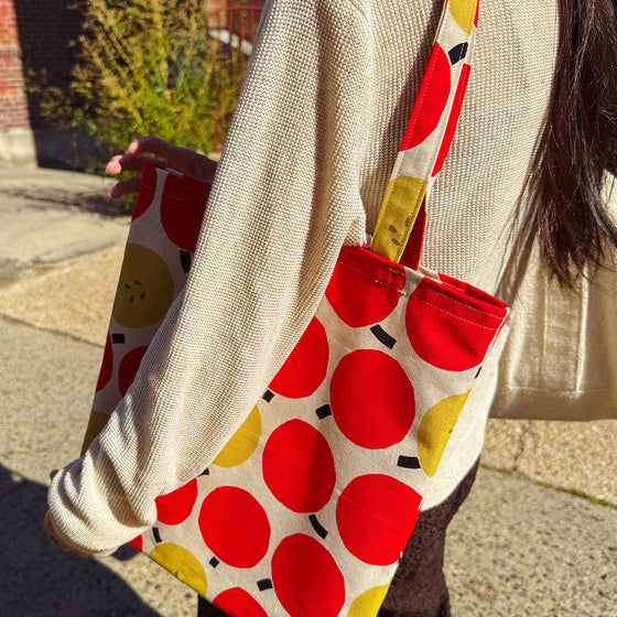 Person holding a tote bag with red and yellow polka dot pattern.