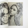 Open book showing a black and white photo of a woman with a spider on her face.