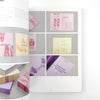 Open book displaying various colorful stationery items on a gray background
